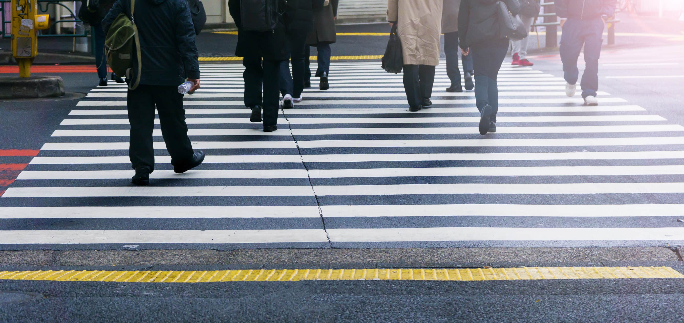 Professionals walk on a pedestrian crosswalk at the junction street of a city.