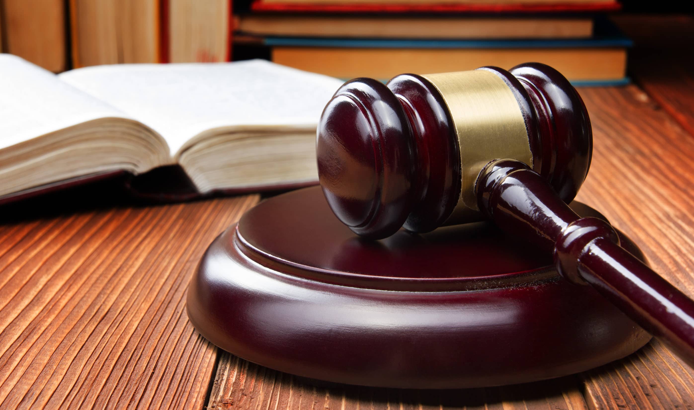 A law book and a judge's gavel sit on a desk.