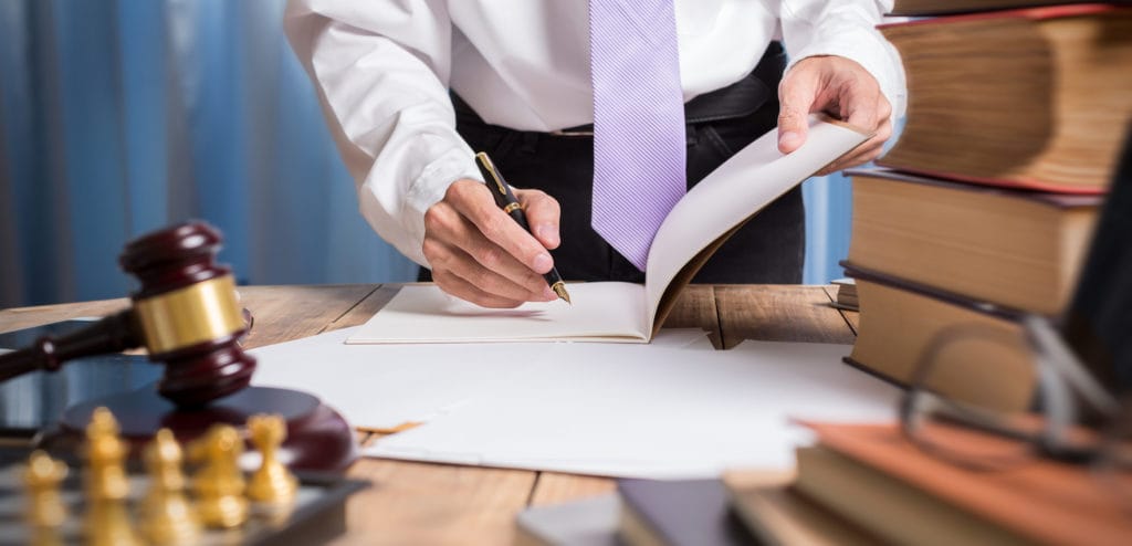 A lawyer signs paperwork on their desk.