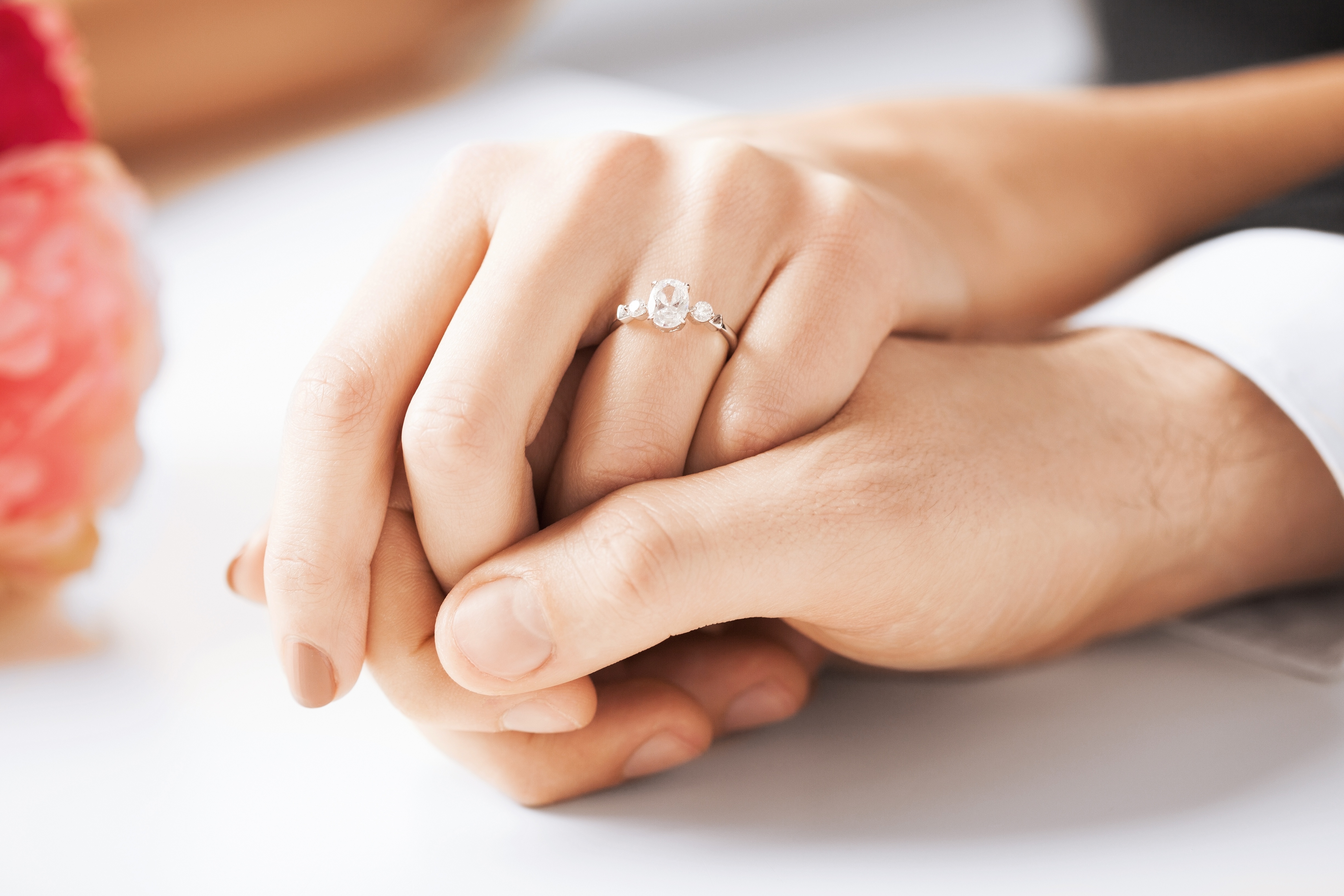 An engaged couple holds hands.